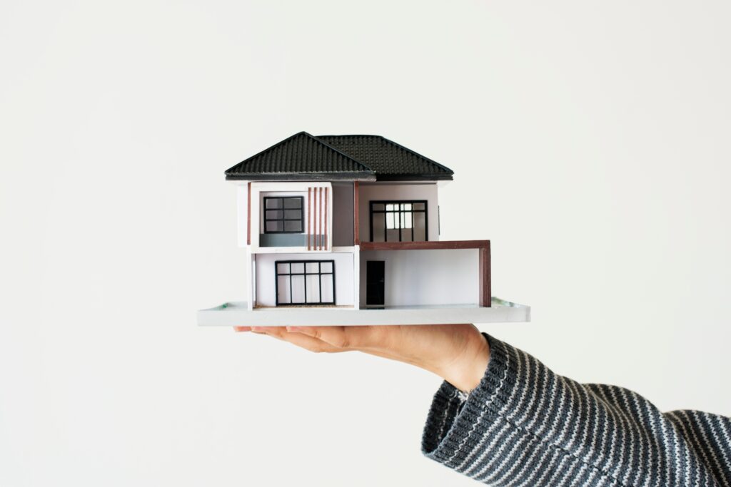 Paid Ads vs SEO for Real Estate - Which Converts Better in 2025? 1 hand presenting model house